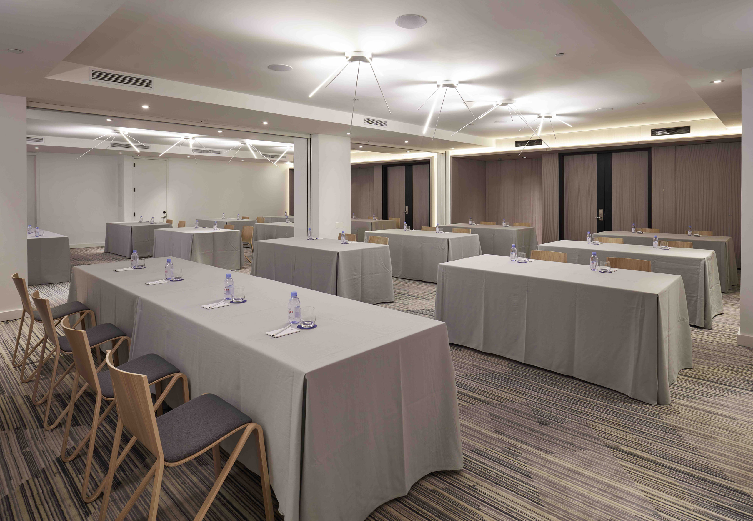 Classroom-style meeting room with tables, chairs, and bottled water.