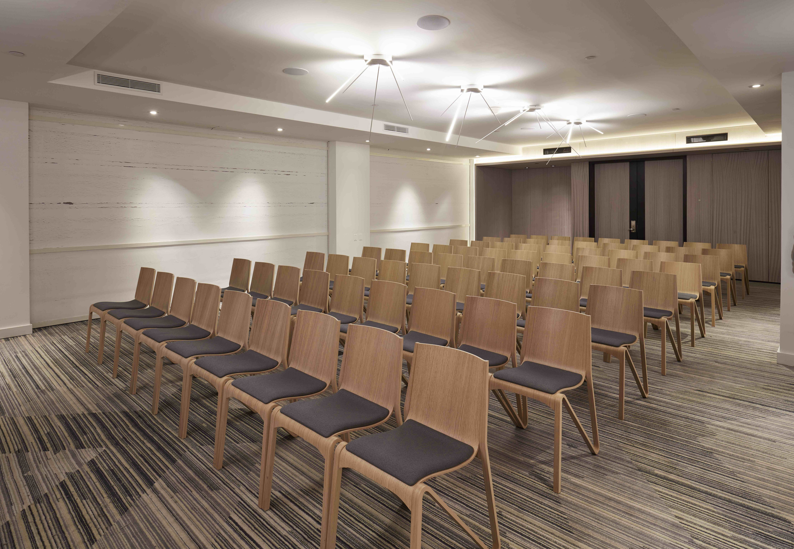Theater-style conference room setup with rows of wooden chairs.