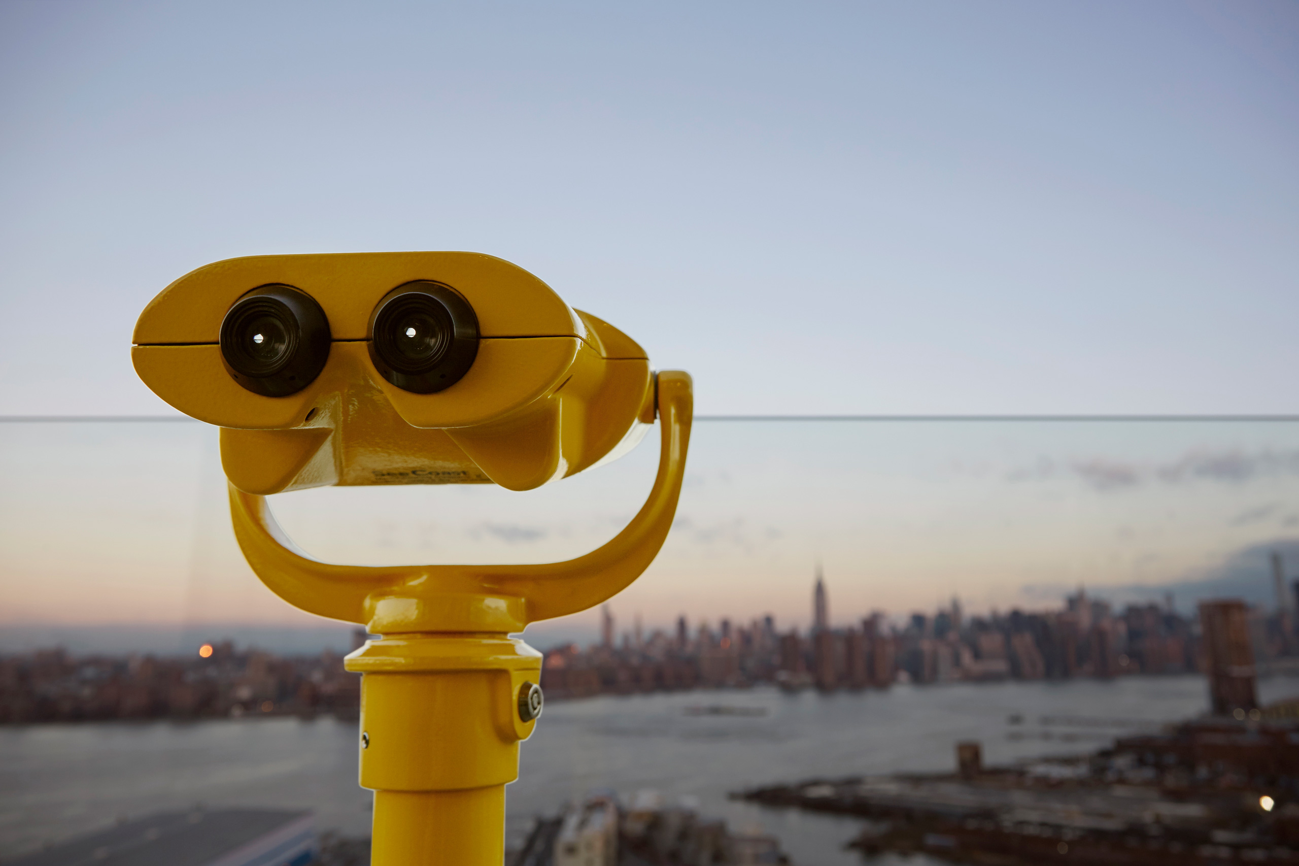 Yellow binocular viewer overlooking Manhattan skyline.