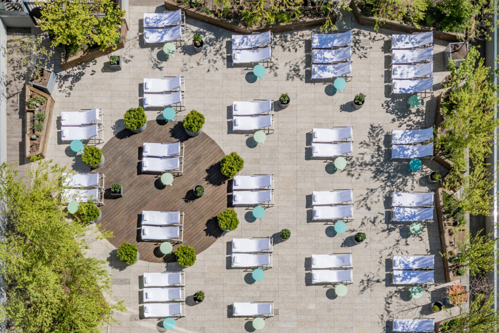 Aerial view of rooftop terrace with lounge chairs and small tables.
