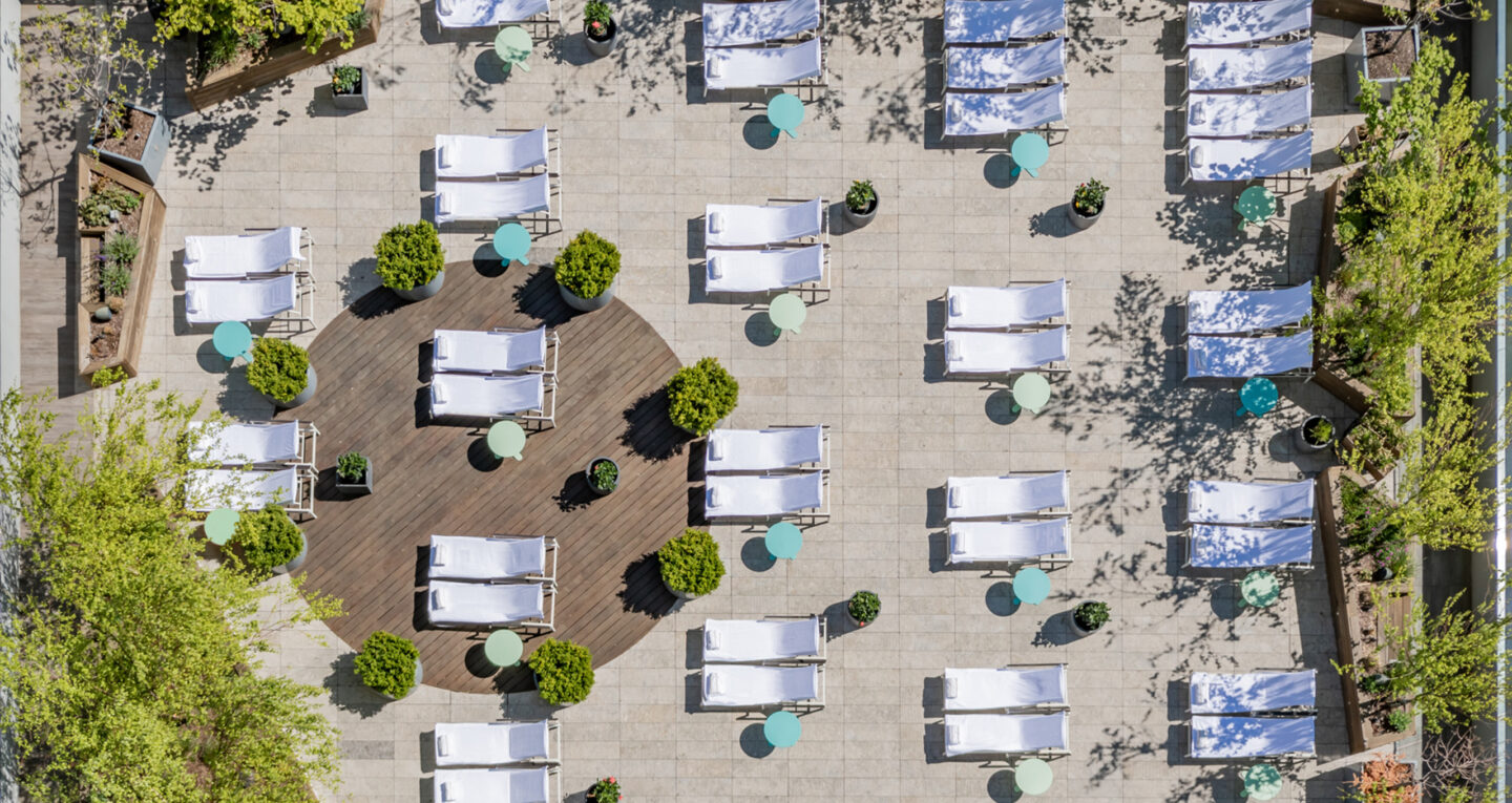Aerial view of rooftop terrace with lounge chairs and small tables.