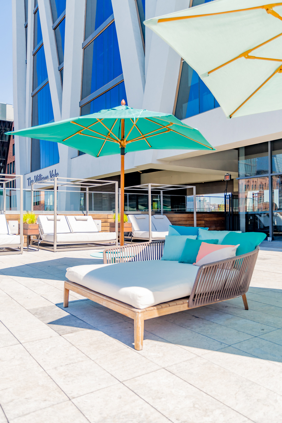 Poolside daybed under turquoise umbrella.