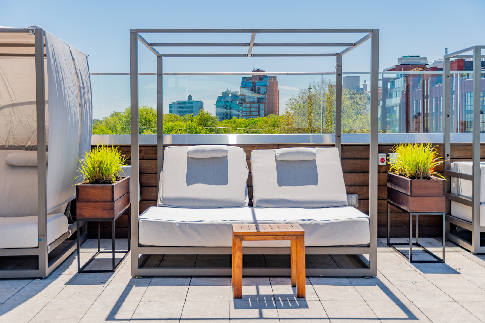 Rooftop double lounger with glass railing view.