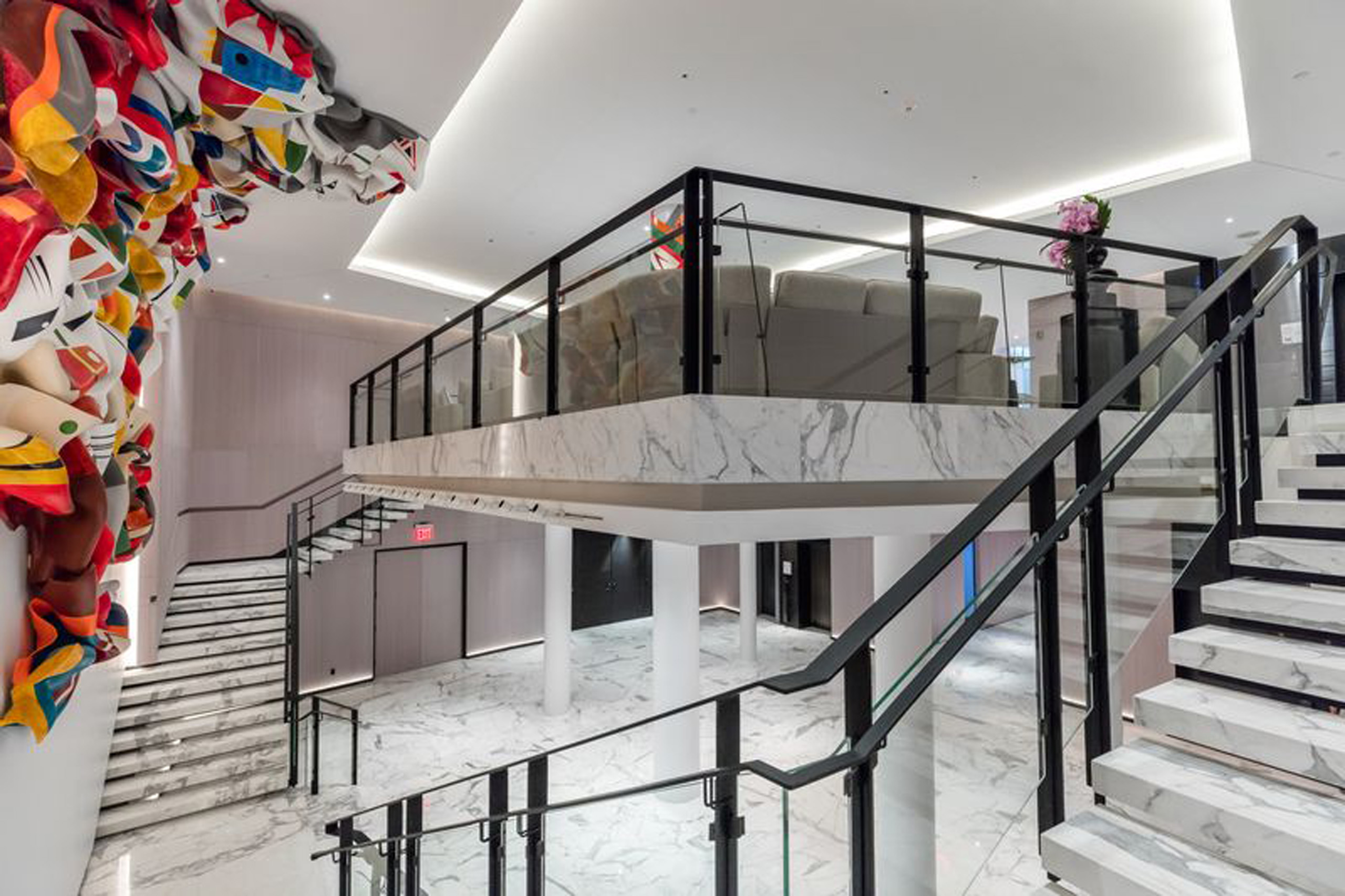 Stylish marble foyer with curved staircase and mezzanine lounge area.