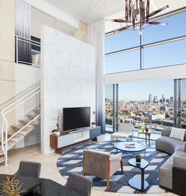 Stylish living room with TV, stairs, and skyline view.