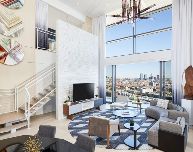 Stylish living room with TV, stairs, and skyline view.