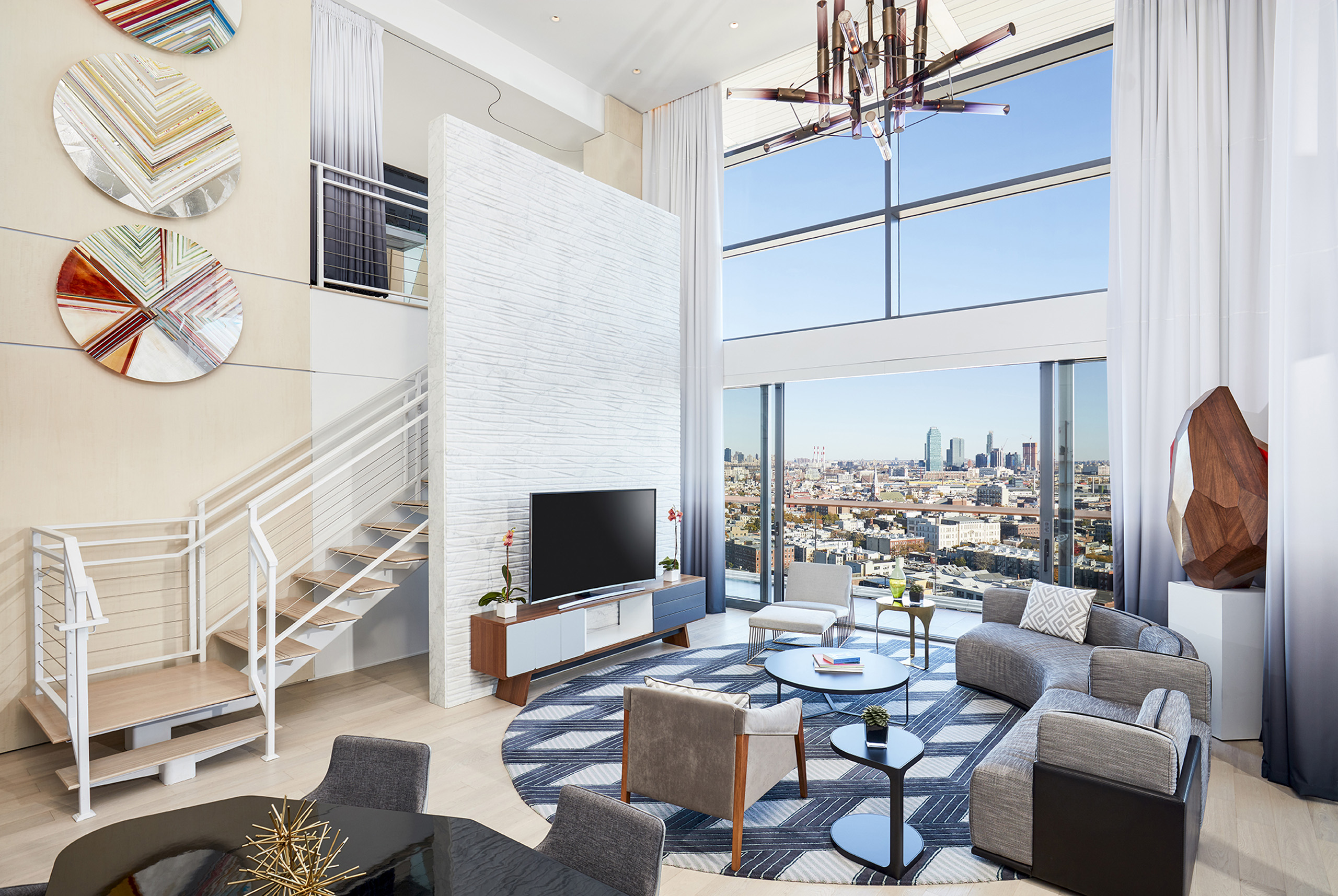 Stylish living room with TV, stairs, and skyline view.