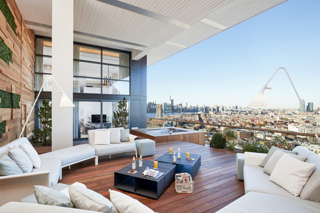 Spacious terrace with sofas, hot tub, and city view.
