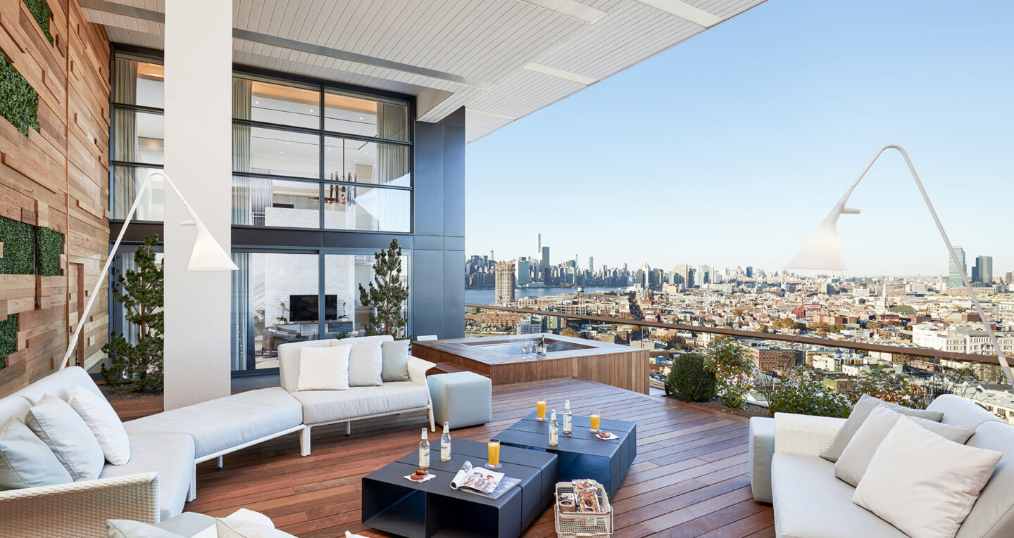 Spacious terrace with sofas, hot tub, and city view.