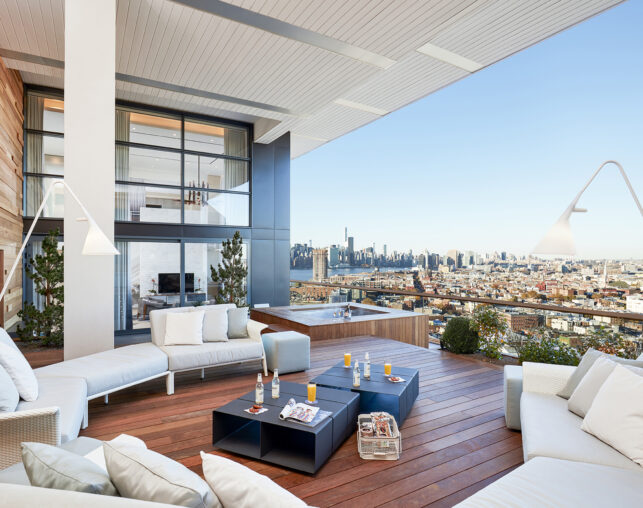 Spacious terrace with sofas, hot tub, and city view.