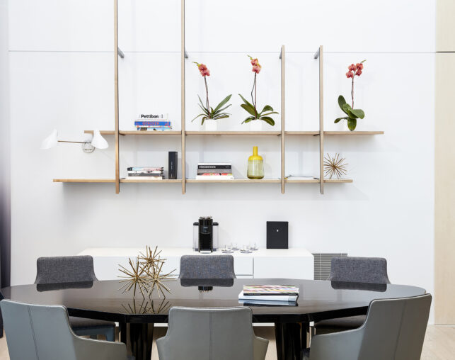 Dining room with decorative shelves and orchid arrangements.