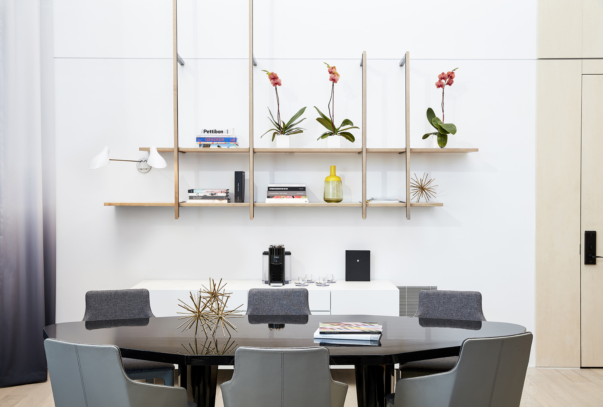 Dining room with decorative shelves and orchid arrangements.