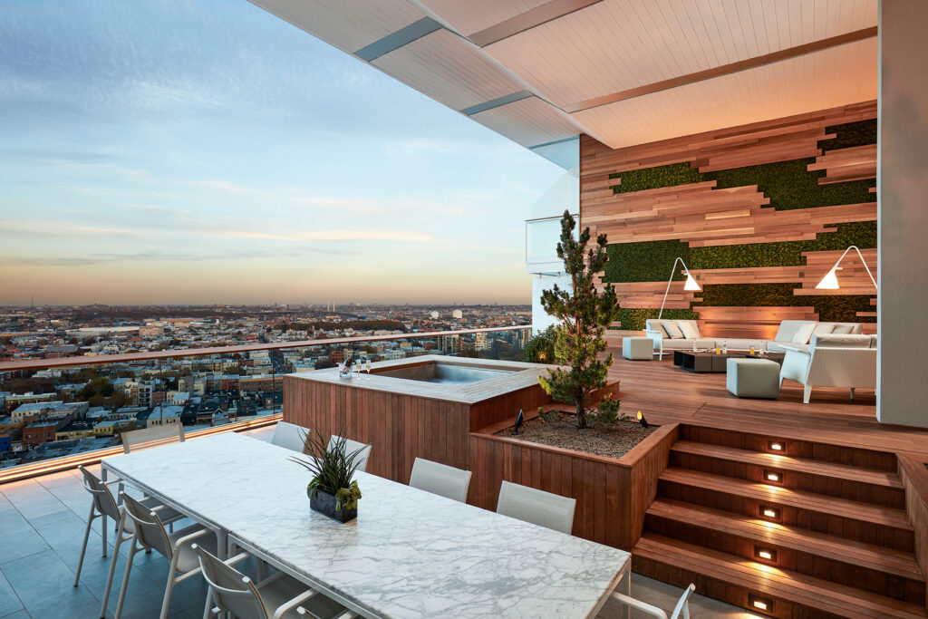 Rooftop terrace with marble dining table, hot tub, and city view.