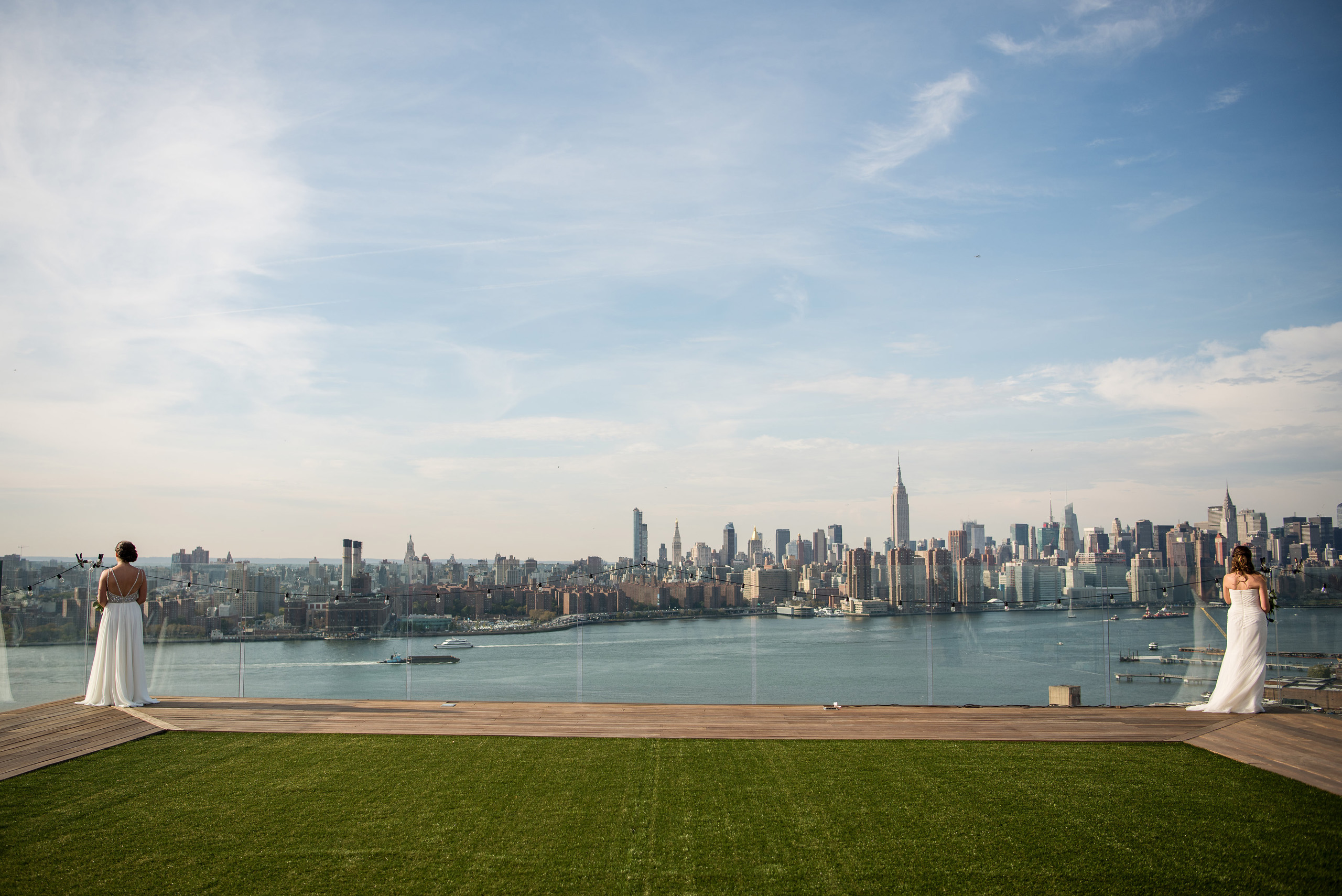 Brides on rooftop overlooking city skyline.