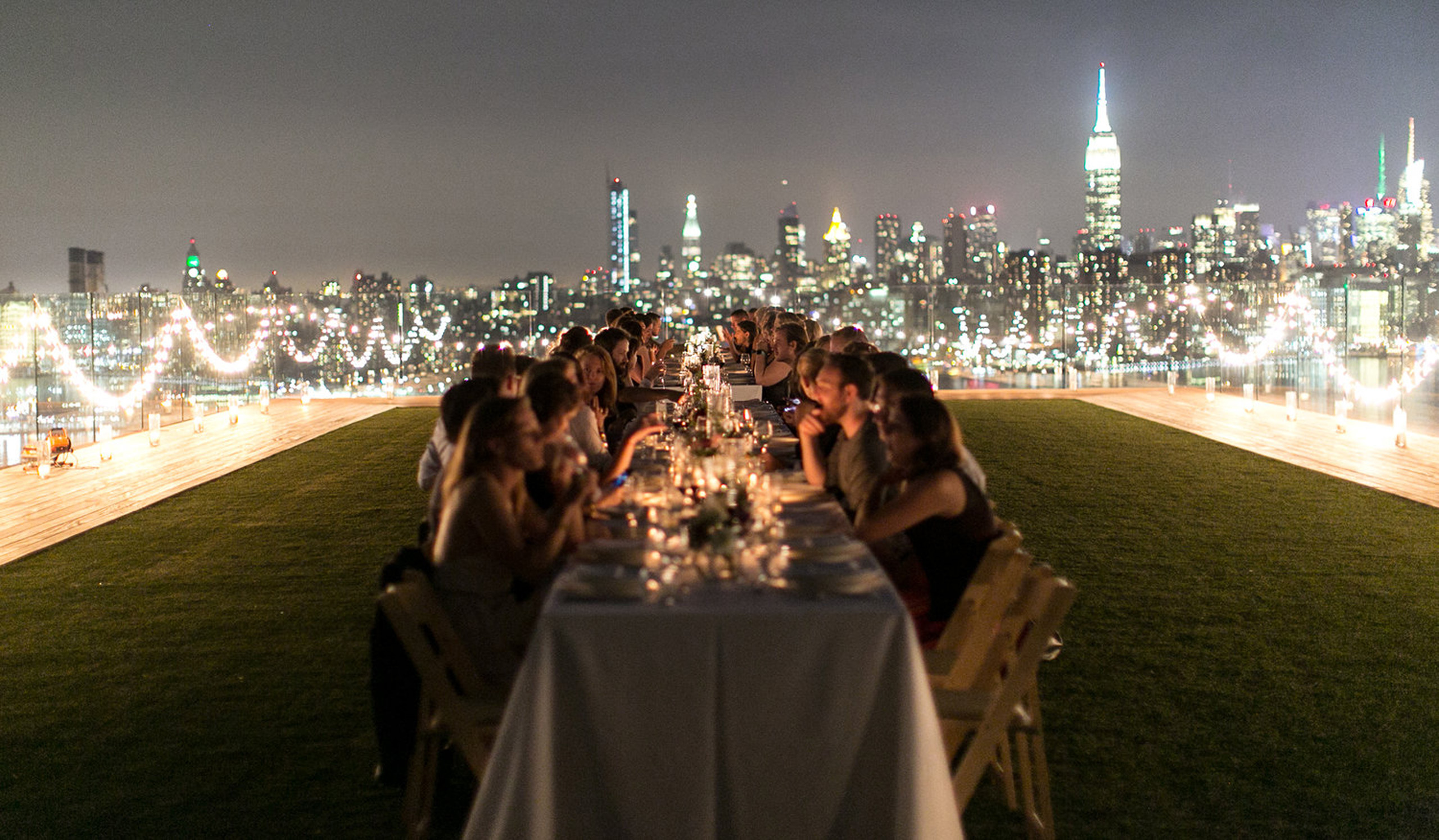 Rooftop dinner party with city lights at night.