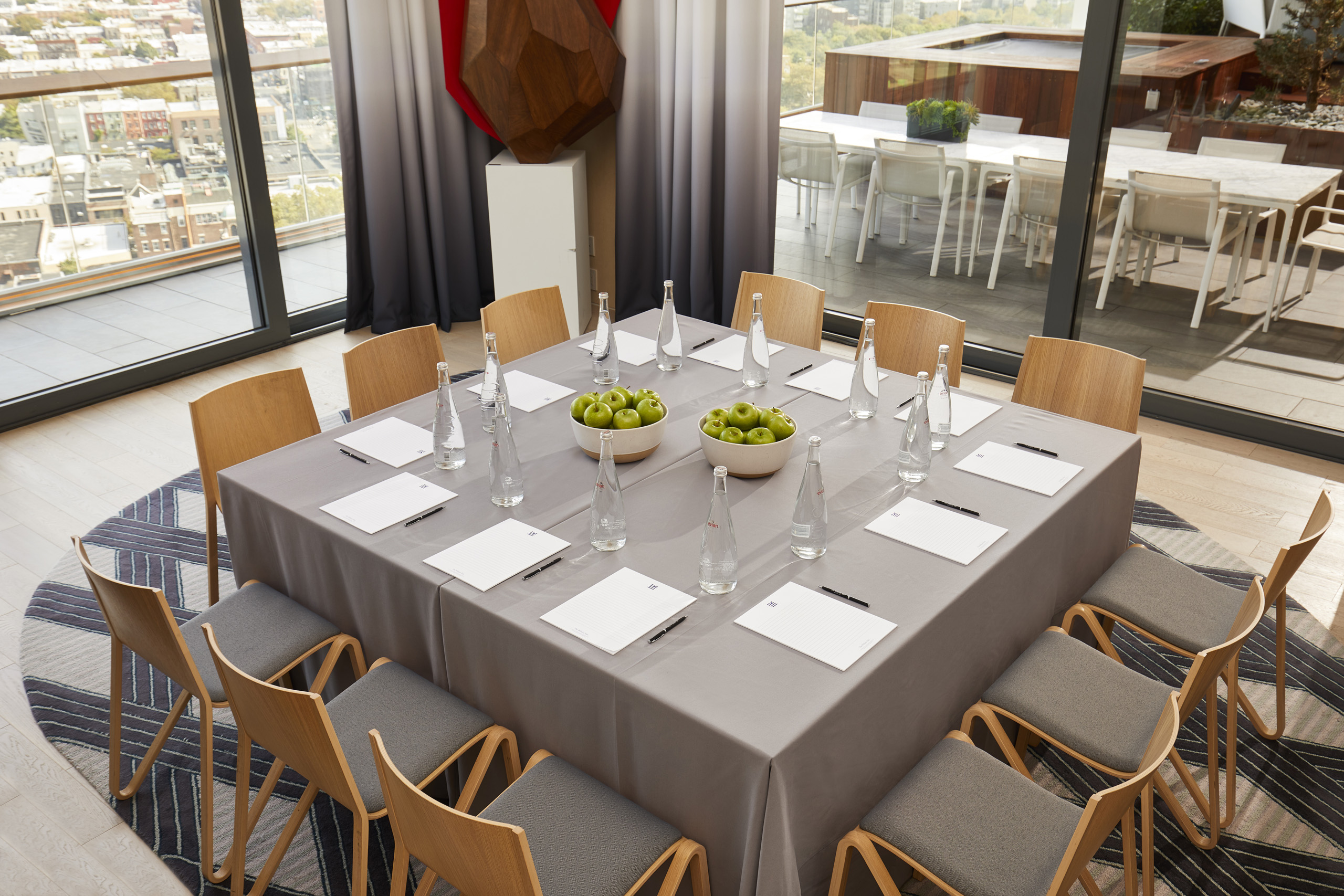 Square boardroom setup with apples and water bottles.