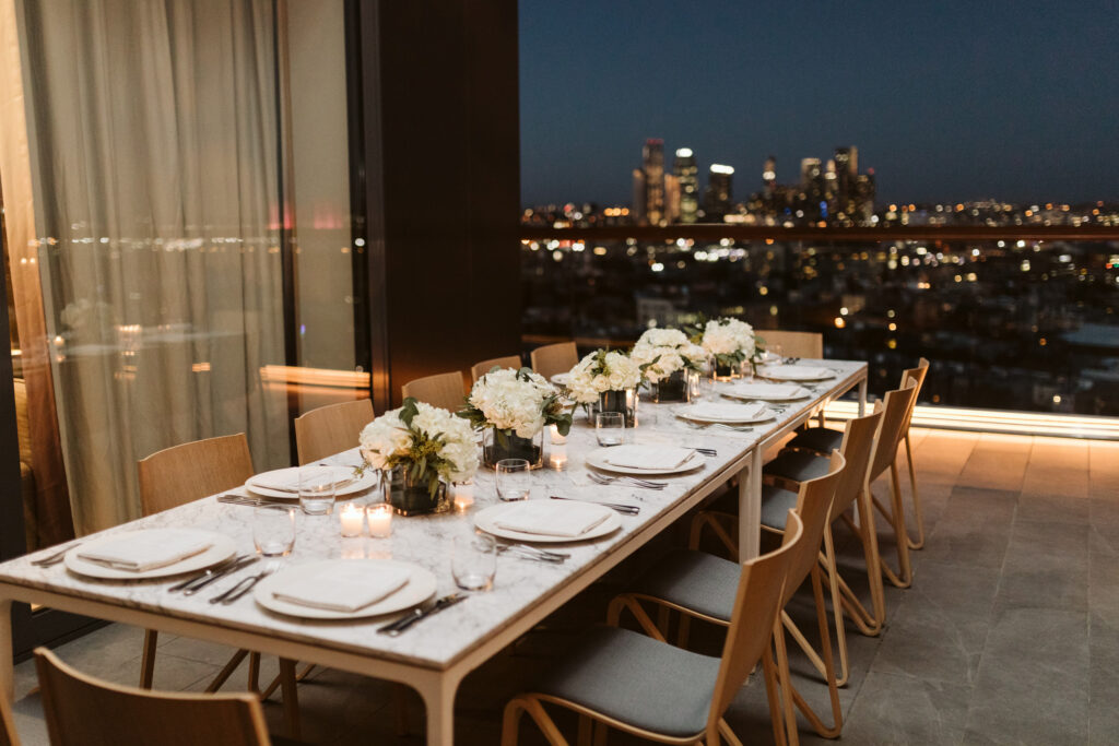 Elegant outdoor dinner table with floral centerpieces at night.