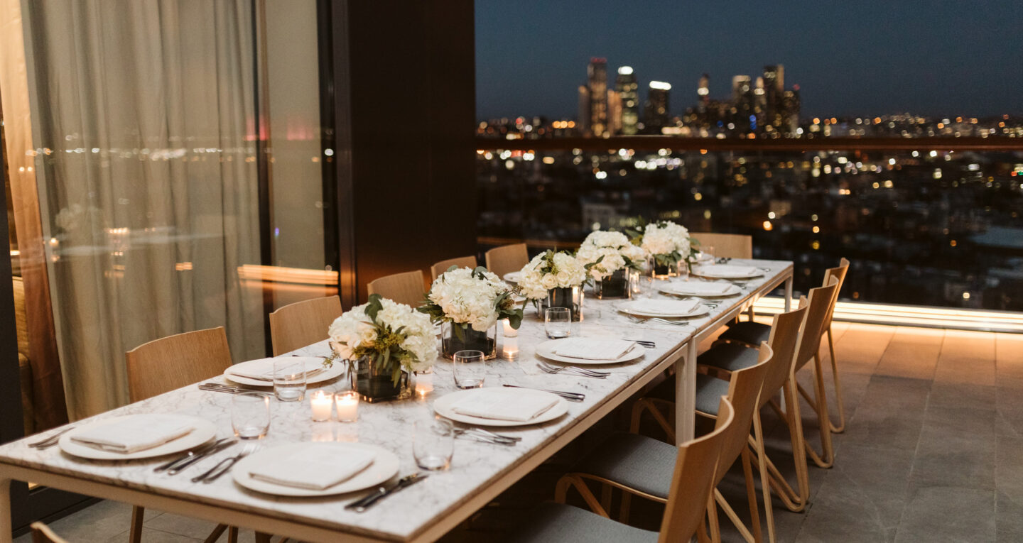 Elegant outdoor dinner table with floral centerpieces at night.