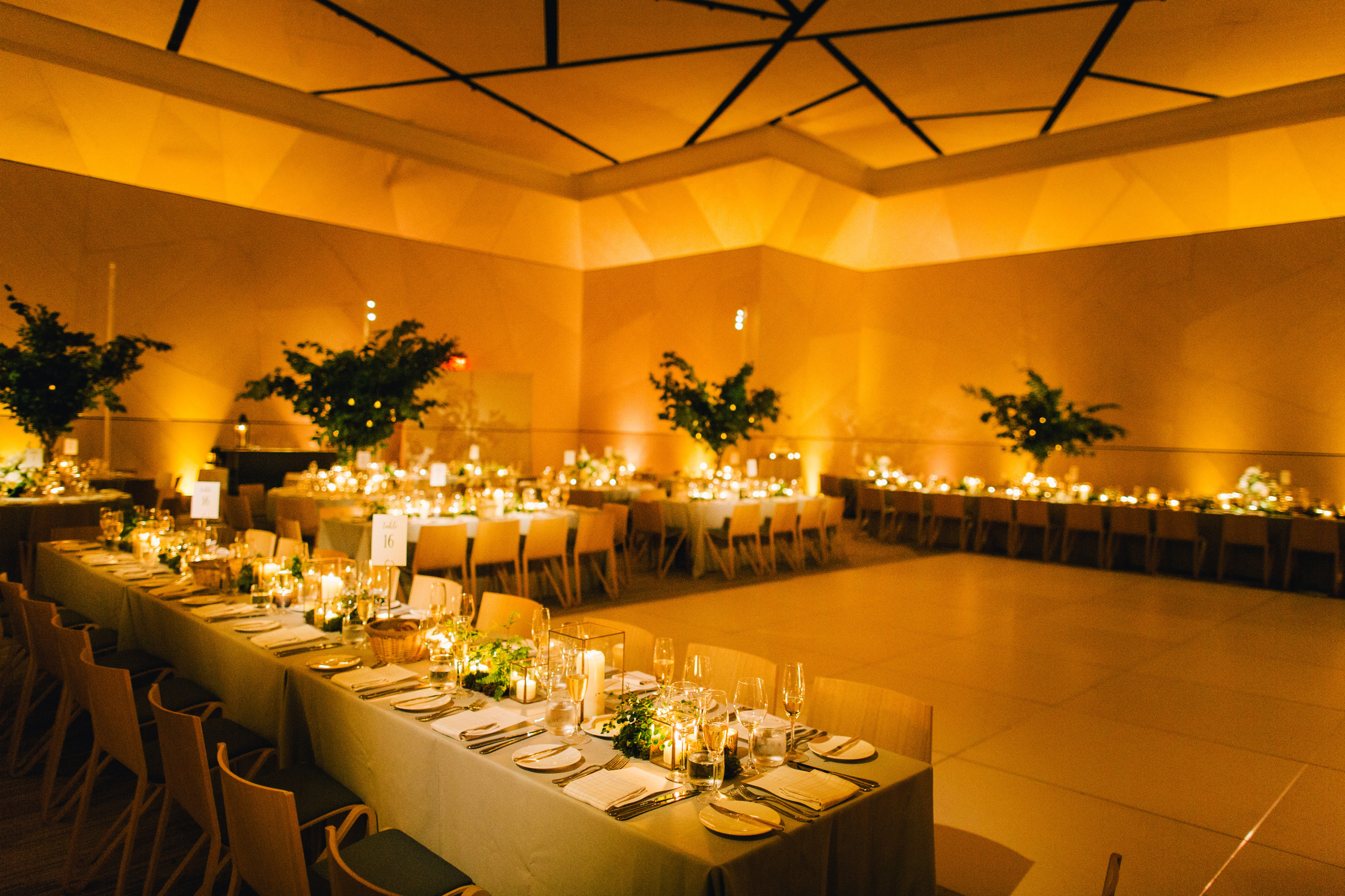 Elegant ballroom reception with long banquet tables, candles, and greenery.