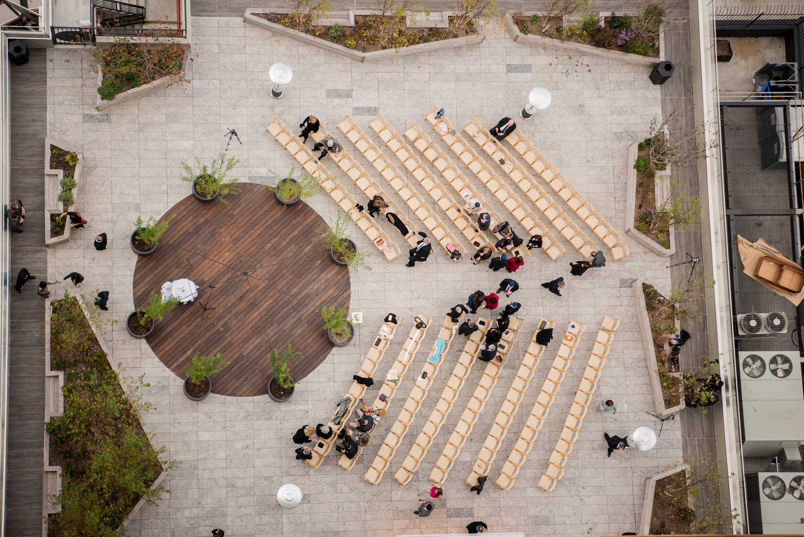Aerial view of outdoor ceremony setup with rows of chairs and circular wooden platform.
