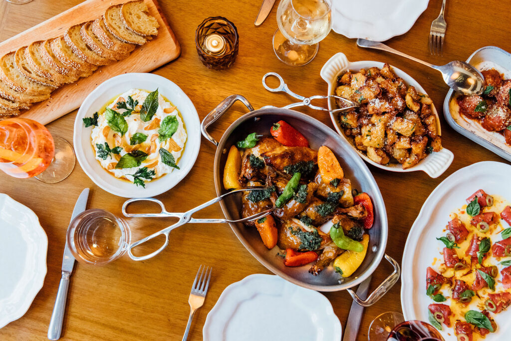 Family-style Italian dinner spread with wine and bread.