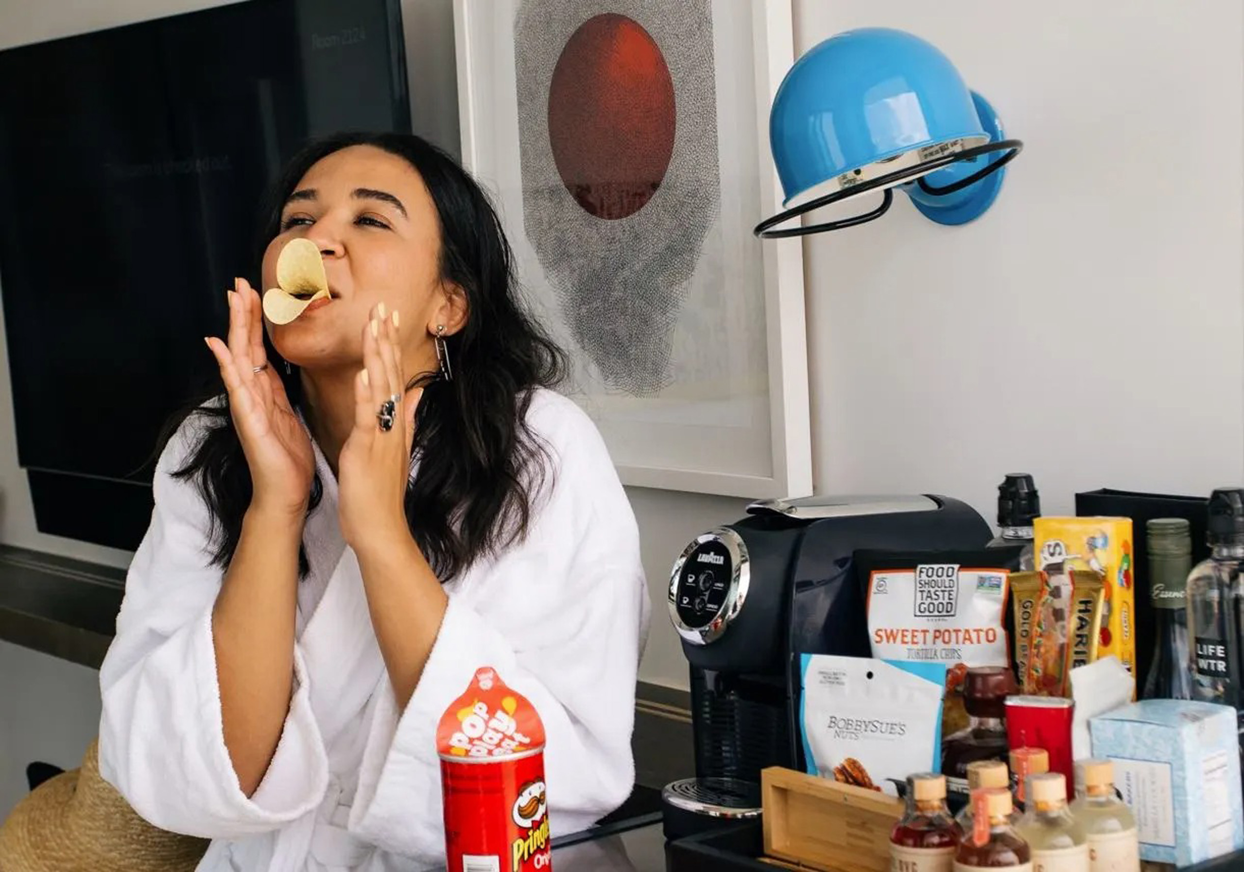 Woman playfully holding chips near stocked minibar.