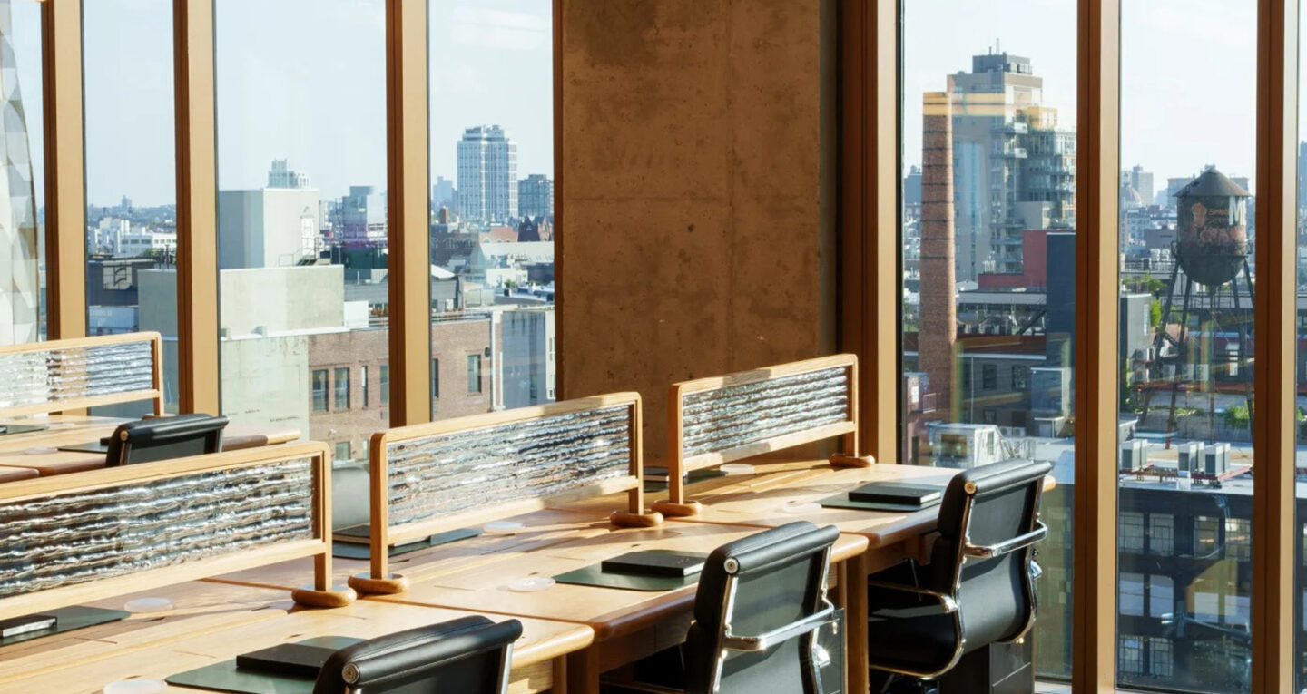 Sunlit workspace with desks and floor-to-ceiling windows.