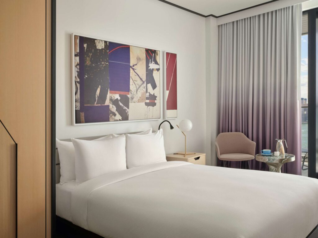 Modern hotel room with bed, abstract art, and balcony
