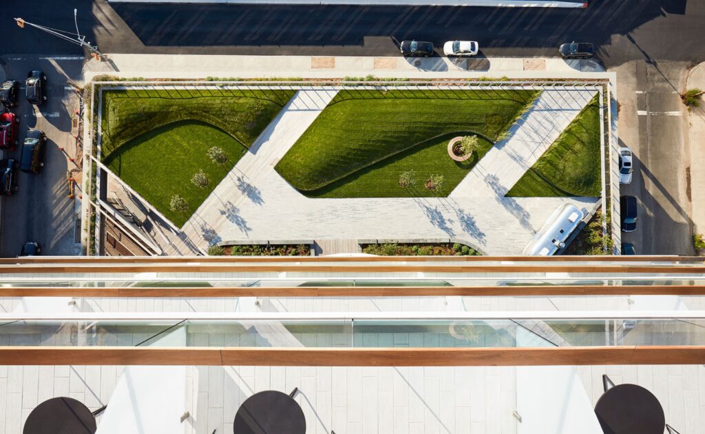 An overhead view of a rooftop garden with green spaces and outdoor seating areas.