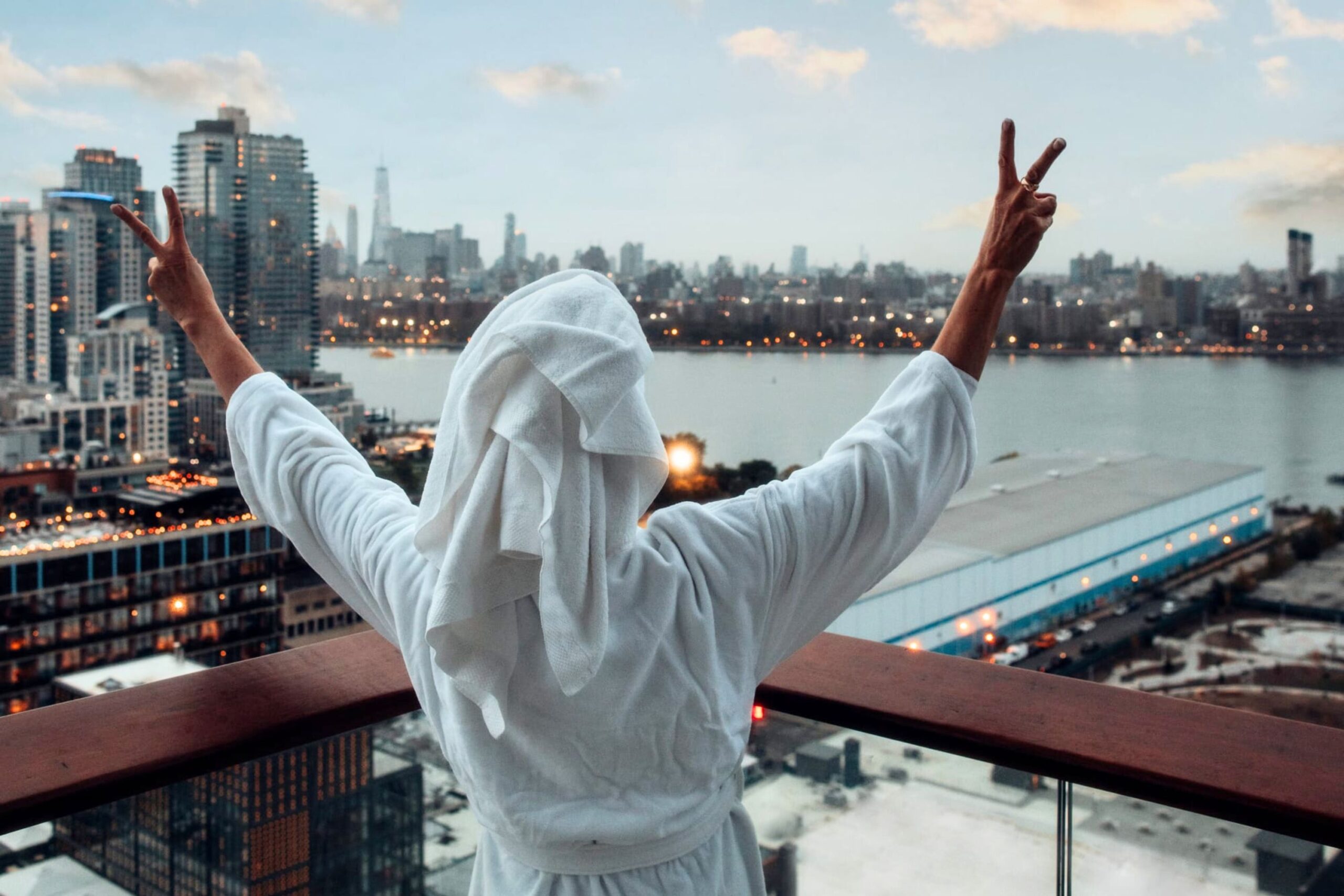 Guest in robe flashing peace signs over skyline.