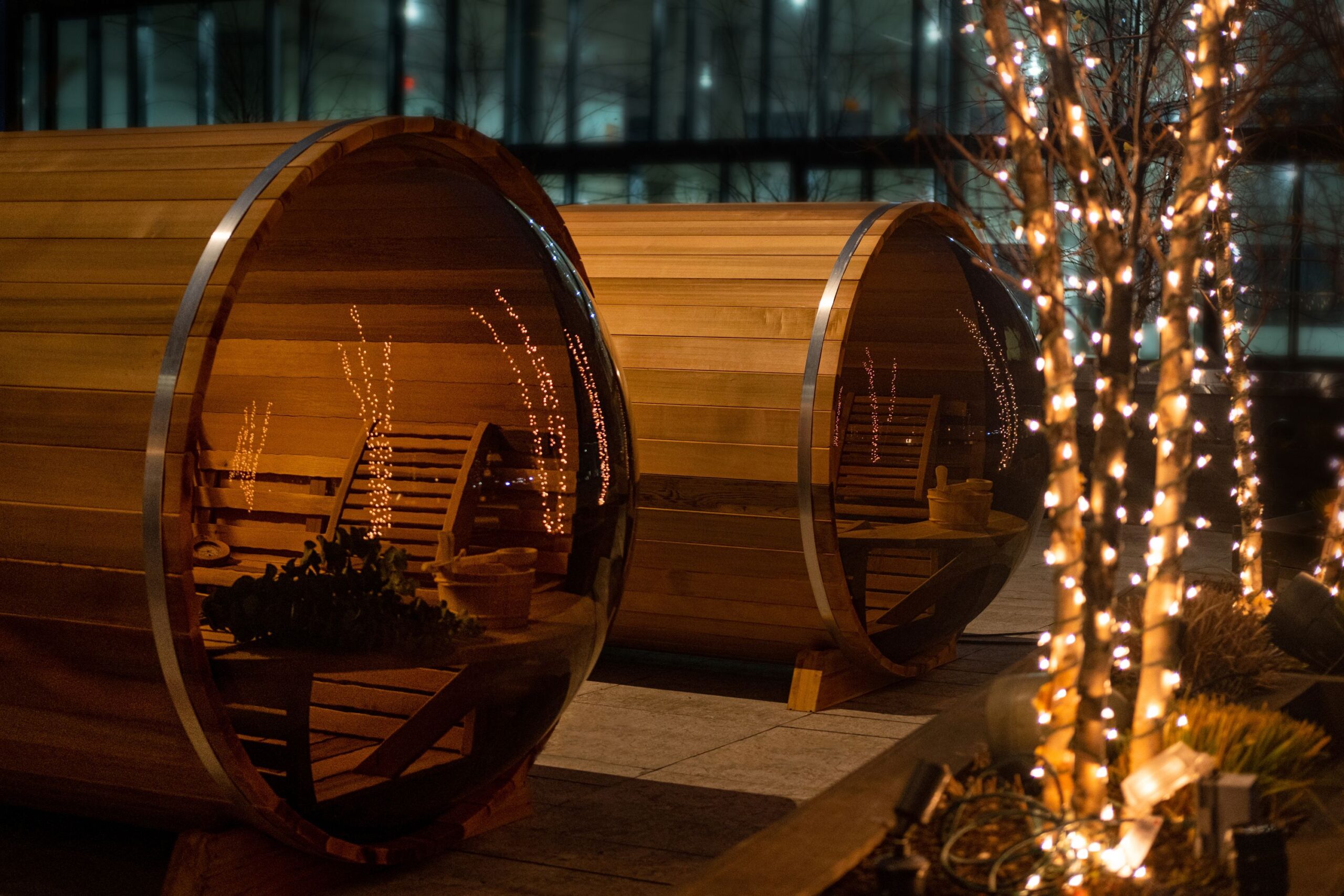 Barrel saunas sit illuminated at night.