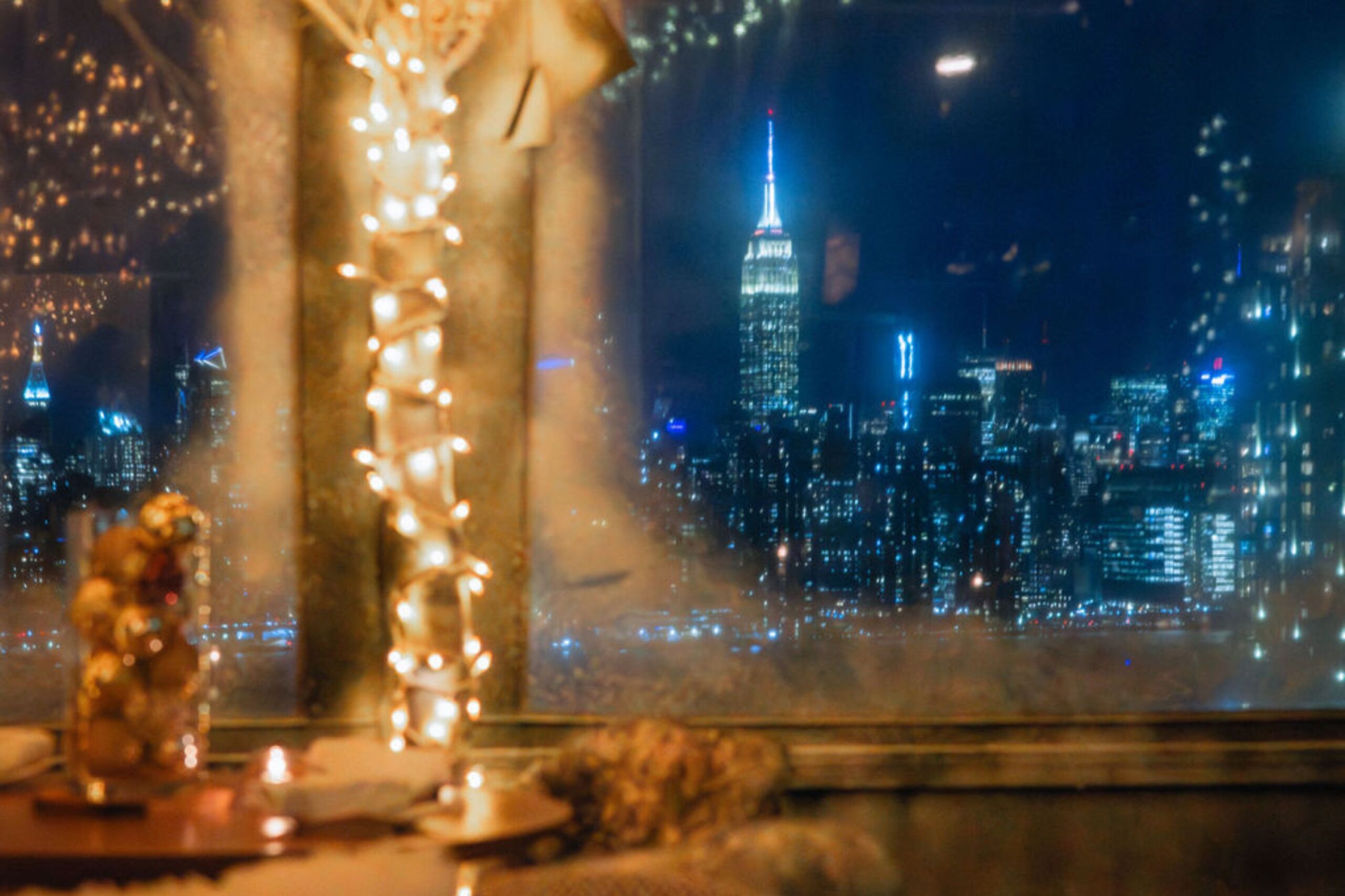 The Empire State Building glows in the distance from the winter wonderland of Snow Lodge at Westlight.