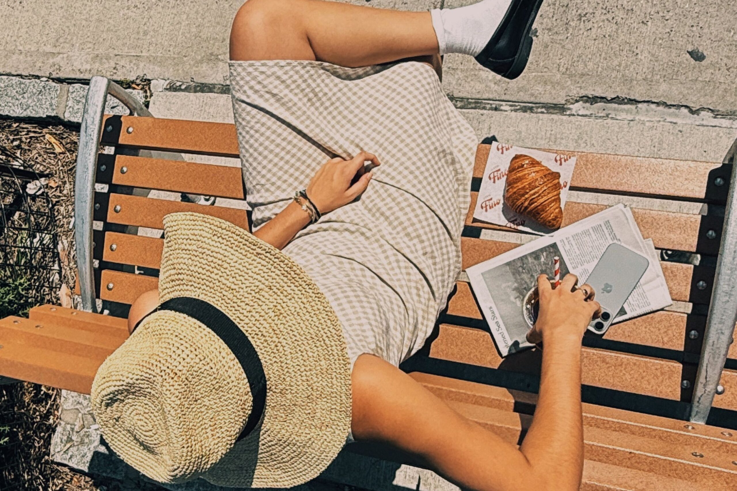 Guest sits on bench while enjoying a coffee and pastry.