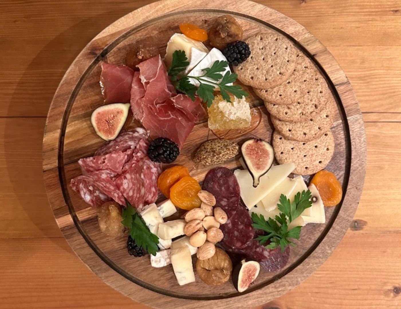 Charcuterie board sits on a wooden table.