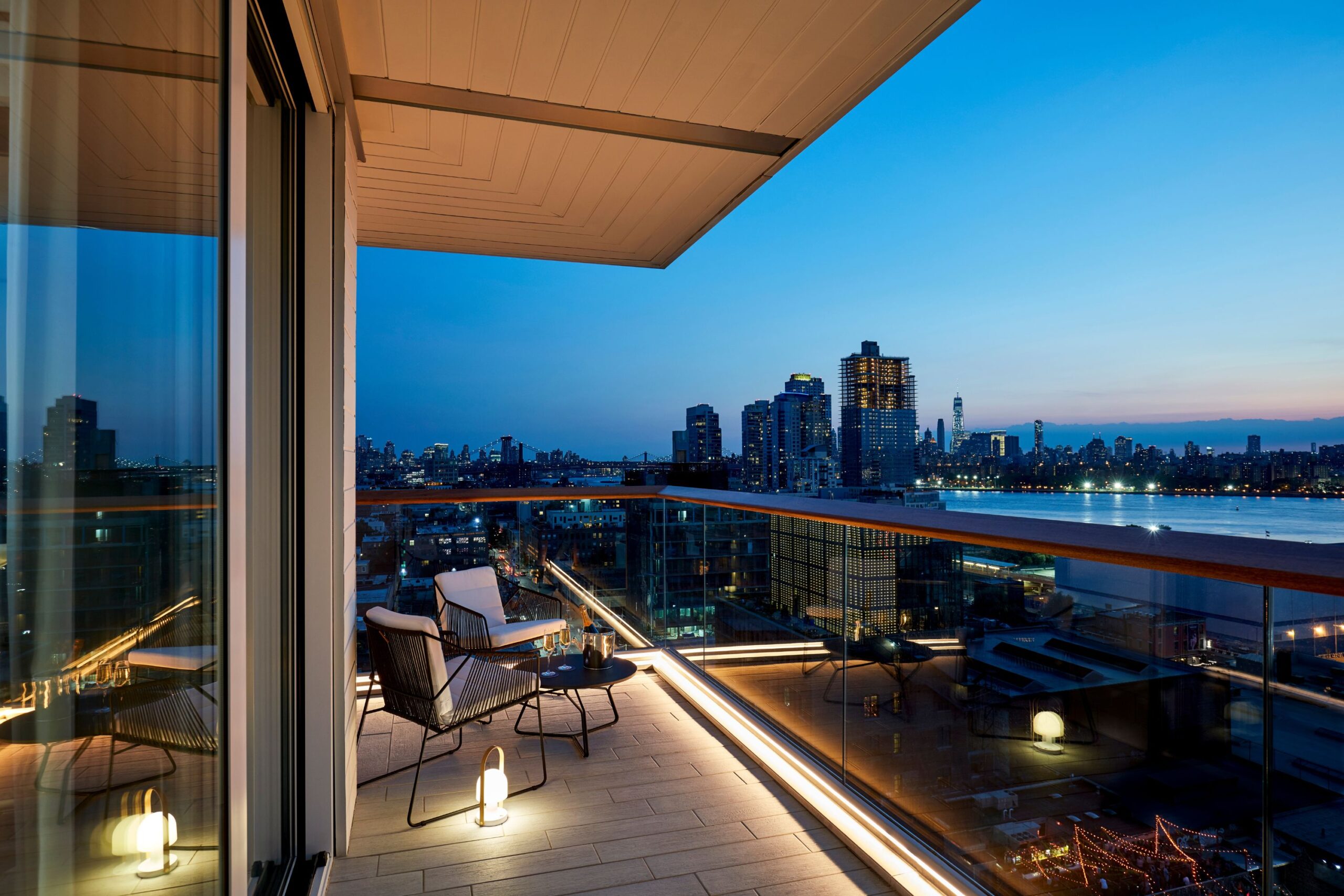 Manhattan skyline glows at dusk from a wraparound balcony at The William Vale.