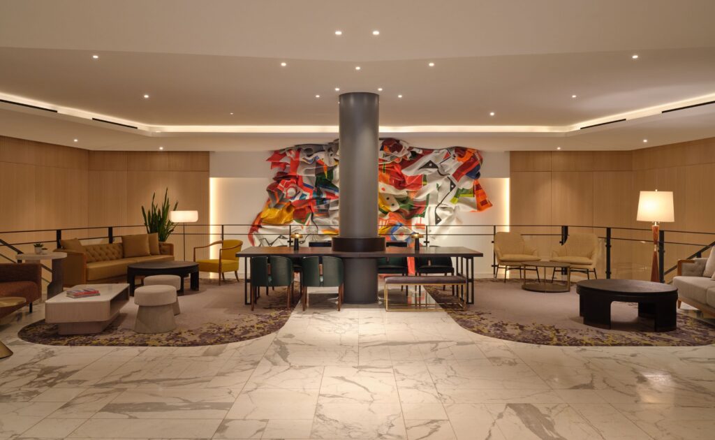 A spacious lobby with a large abstract artwork, comfortable seating, and a dining table.