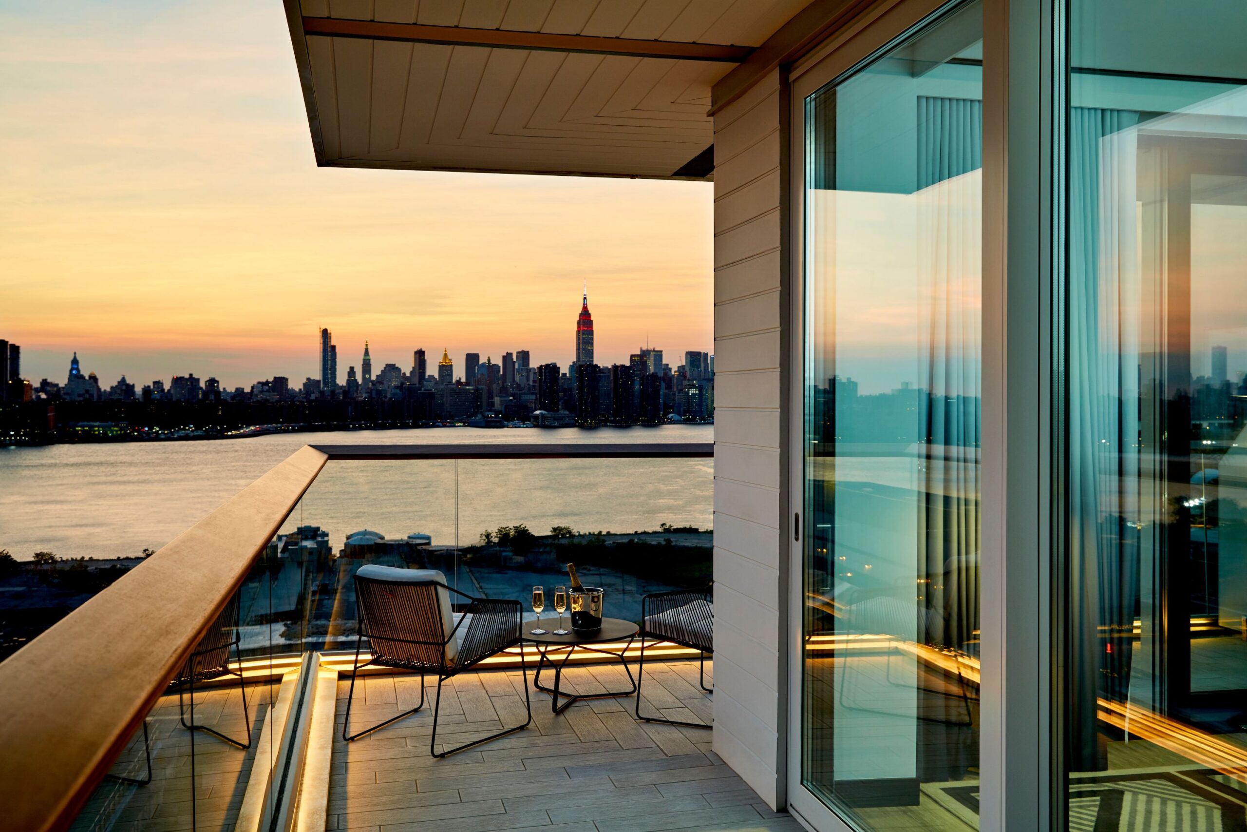 Sun sets behind Manhattan skyline as seen from wraparound balcony at The William Vale.